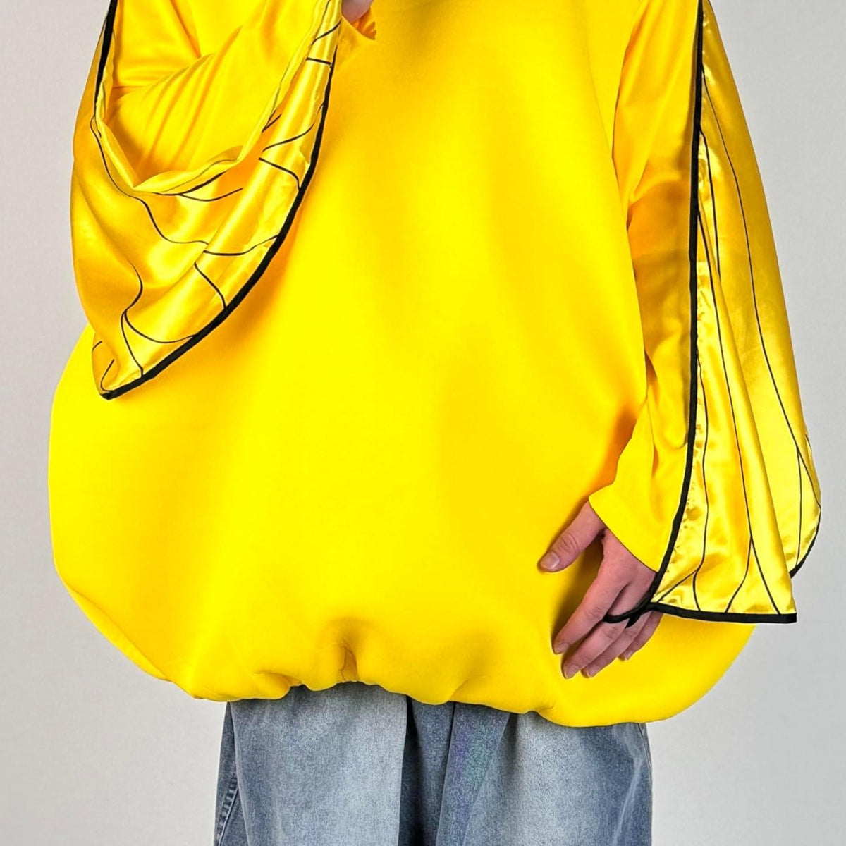 Real-life close-up of the yellow duck costume showing the satin wing sleeves, black piping and gathered elastic hem