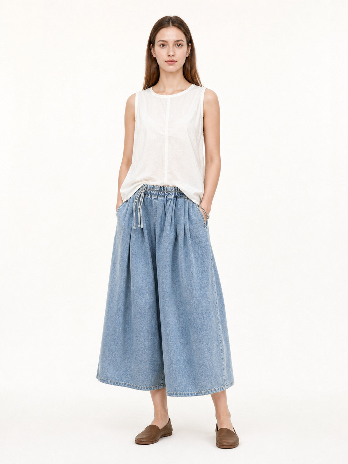 Light blue wide-leg jeans shown full-body on a model, styled with a white sleeveless top and brown flats
