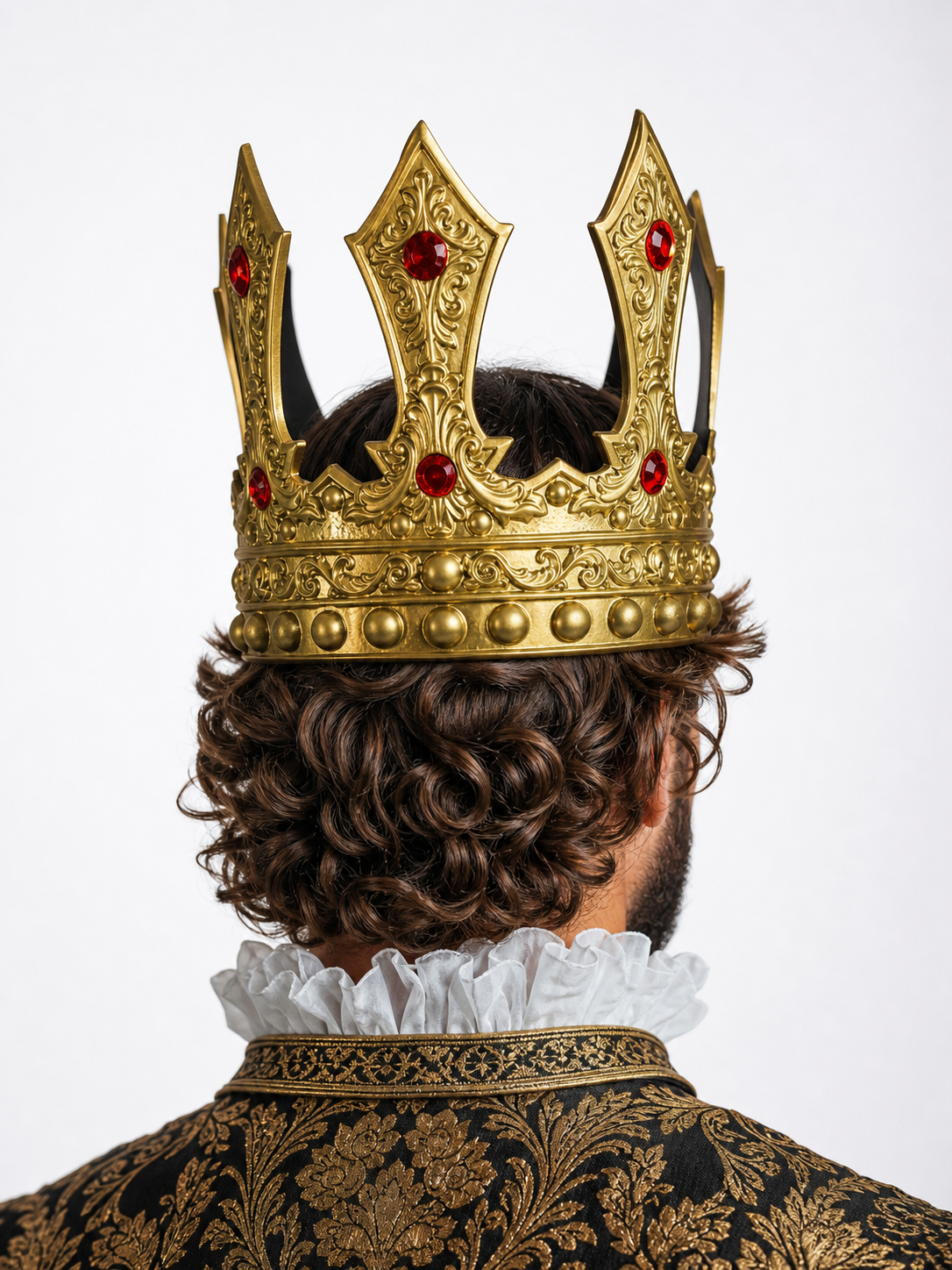 Gold ornate crown with red stones, shown from the back on a man wearing a patterned costume and ruffled collar