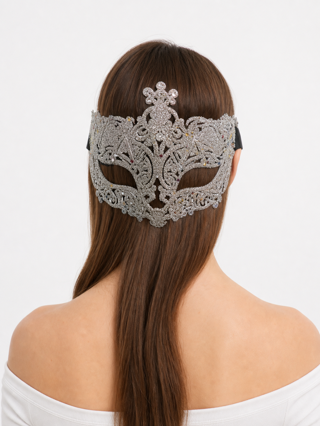 Rear three-quarter view of a woman wearing a silver glitter mask, showing the ornate design, black side tie, and brown hair