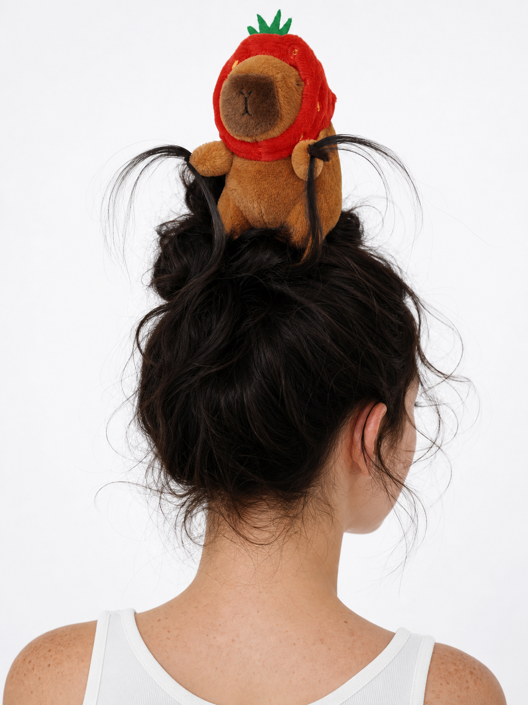 Back view of a model wearing a black headband topped with a plush brown animal in a red strawberry hood and green leaves