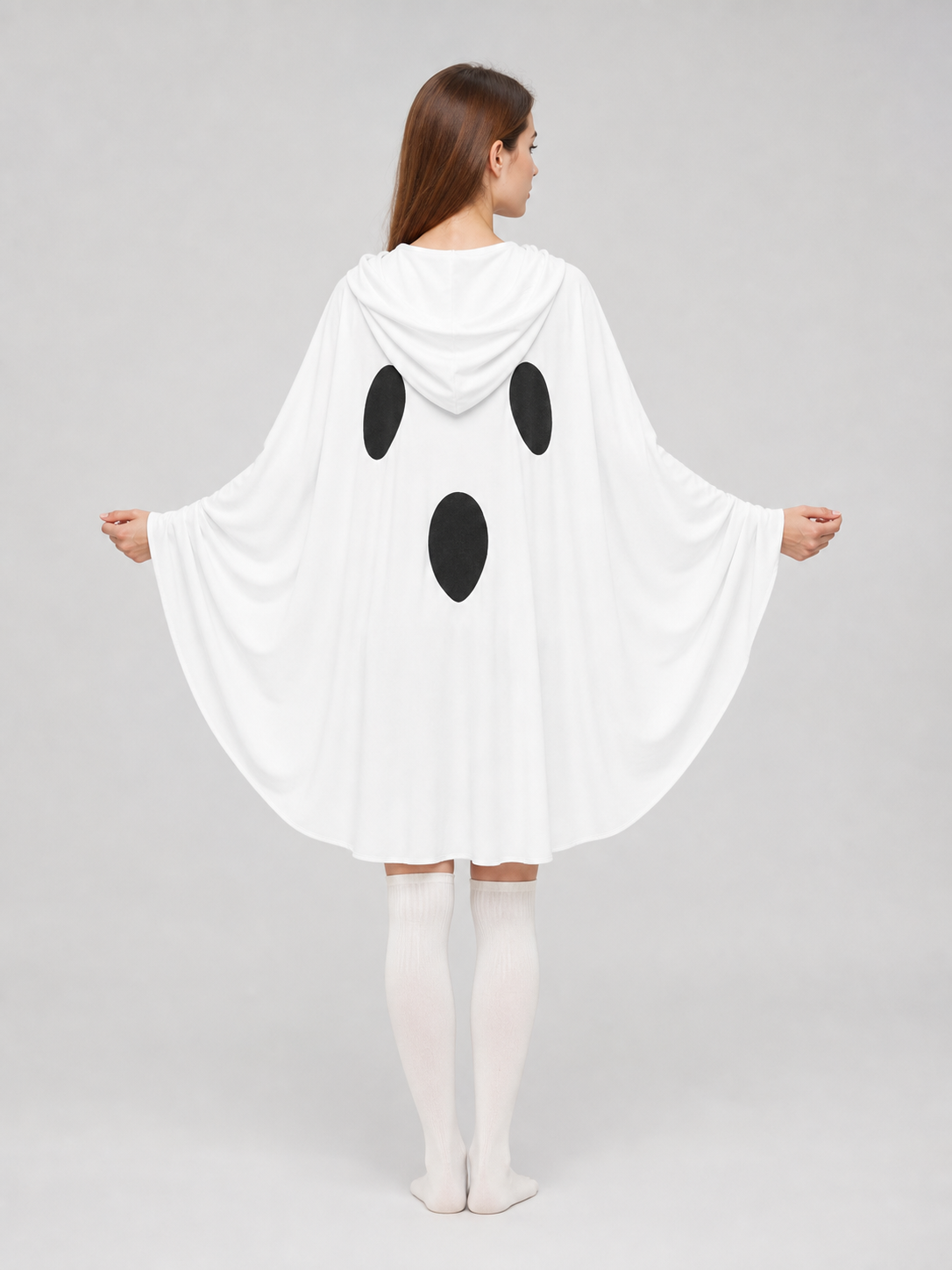 Back view of a white hooded ghost cape on a model, with wide draped sleeves and three black oval patches