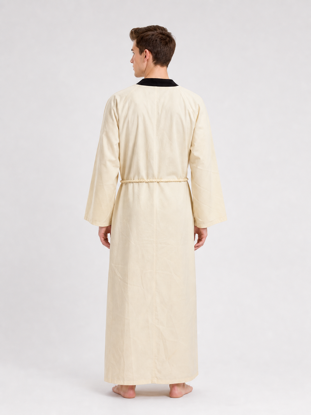 Rear view of a cream long robe showing the black neckline, loose sleeves, straight back, and rope tied at the waist