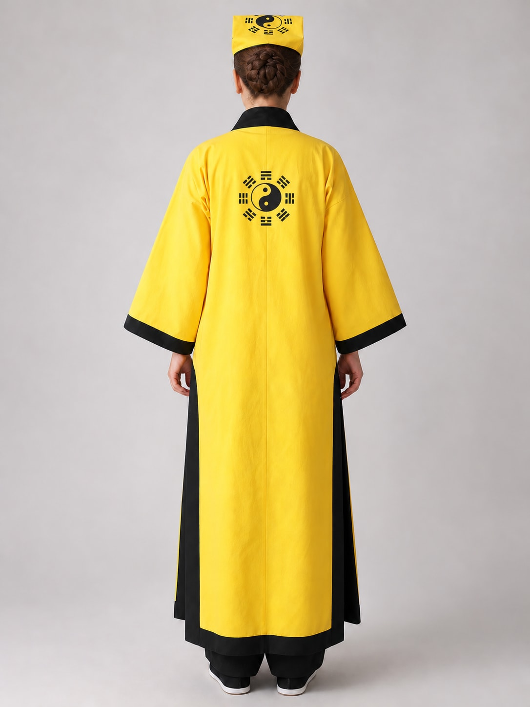 Back view of yellow Taoist priest robe with yin-yang trigram emblem and square hat