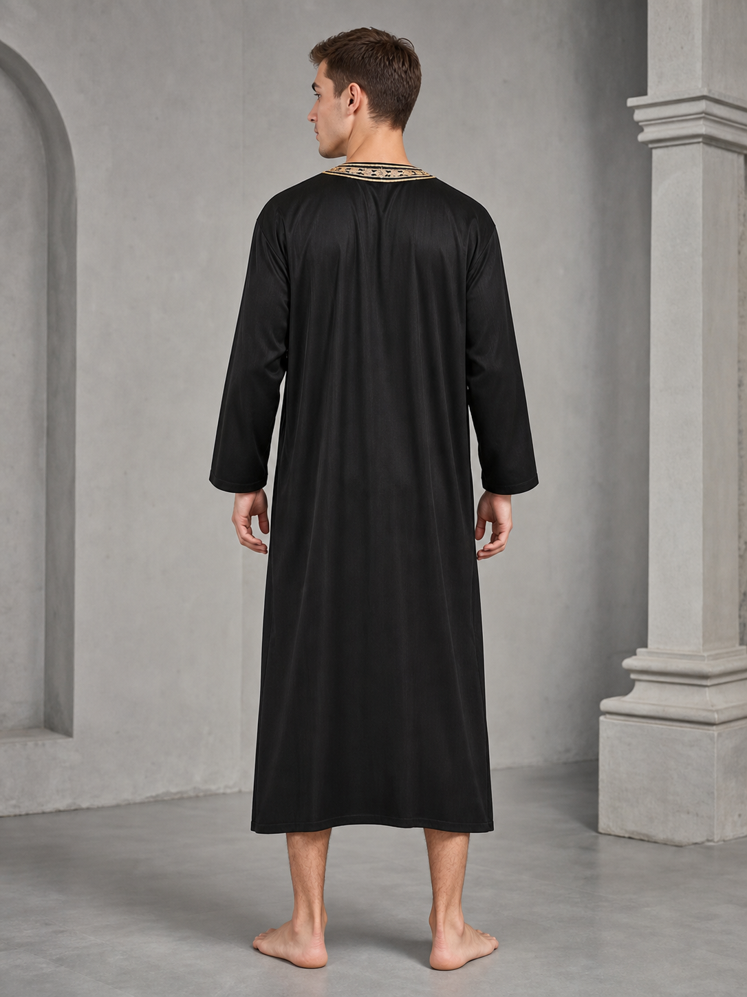 Back view of a man wearing a loose black full-length robe with gold-tone trim visible around the collar