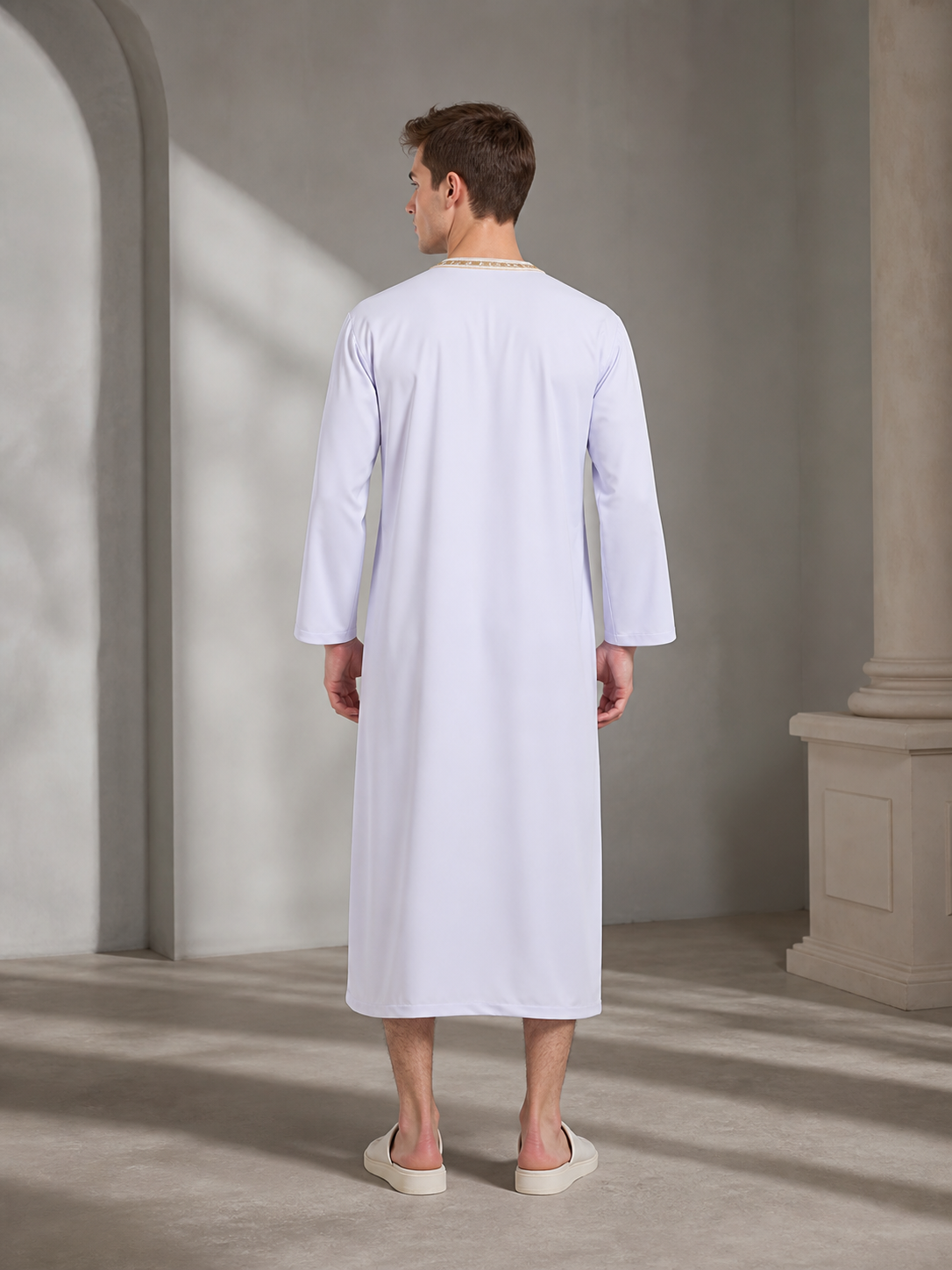 Back view of a white ankle-length robe on a model, showing long sleeves and gold-toned trim around the neckline