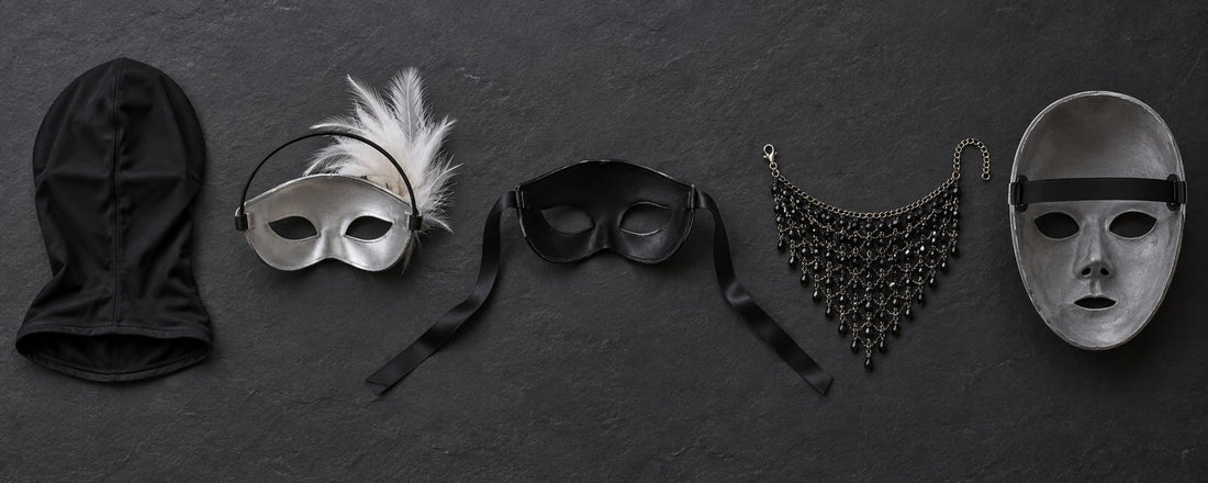 Five costume masks on dark slate: a stretch hood, an eye mask with a headband, a ribbon-tie mask, a chain veil with clasp and a strapped full-face mask