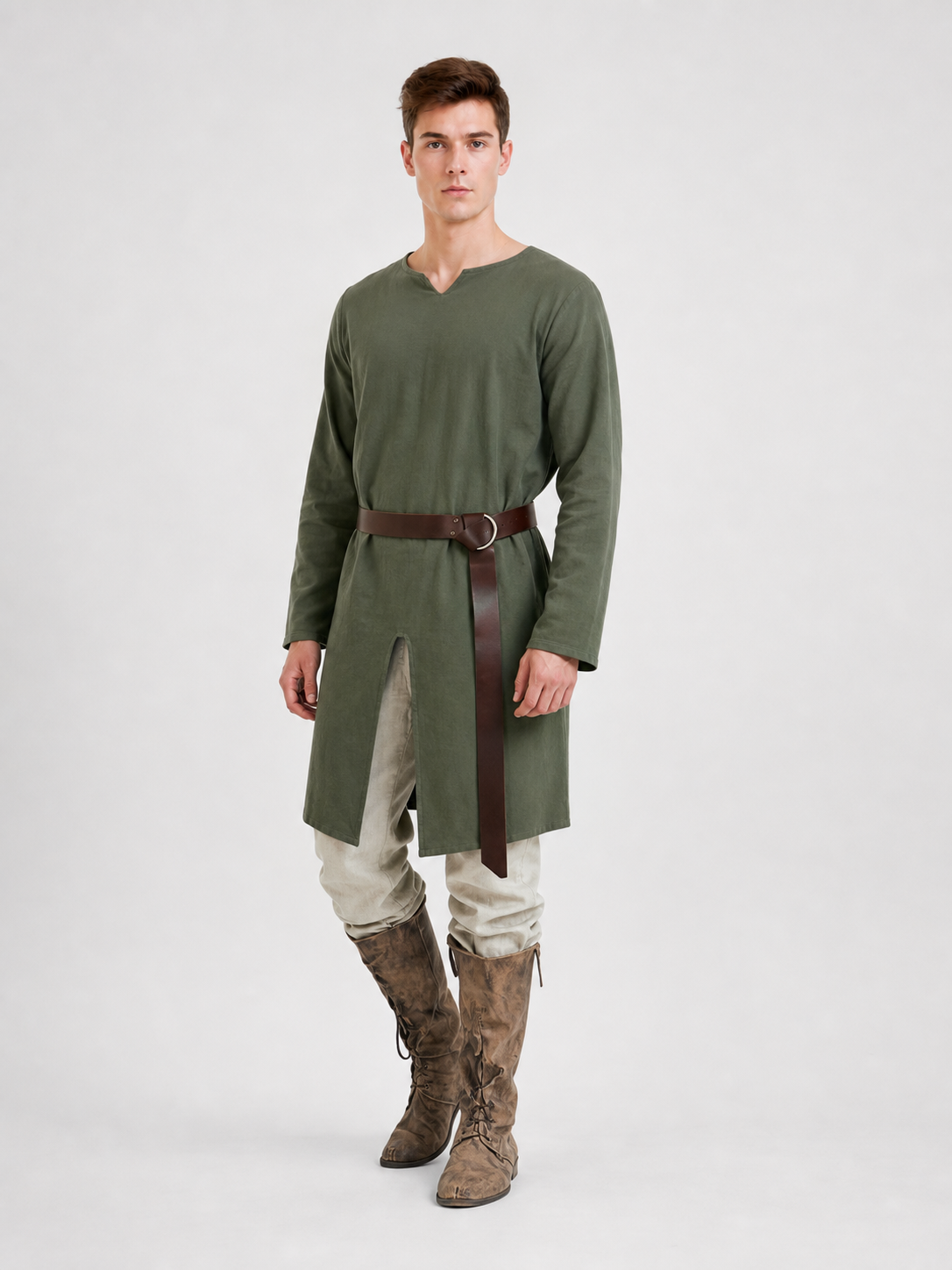 Green long-sleeve tunic shown on a model at three-quarter view, with a brown belt, front slit, cream trousers, and brown boots
