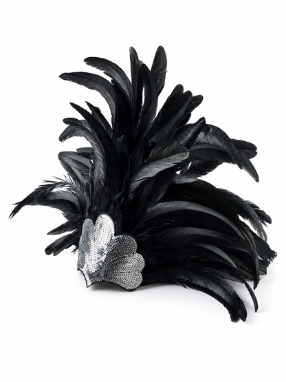 Black feather headpiece with layered feathers and a silver sequined heart centerpiece, shown laid flat