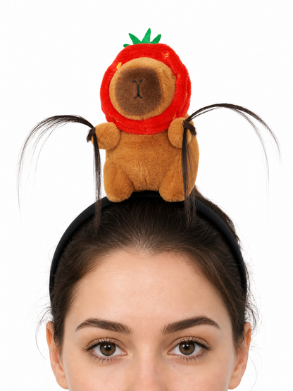 Close-up of a black headband with a plush brown animal, red strawberry hood, green leaves, and long black decorative strands