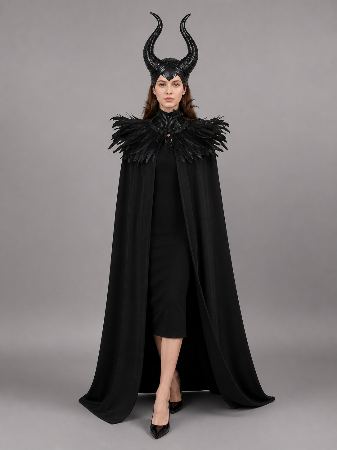 Black costume cape shown full-body on a model, with a long draped silhouette, tall curved horns, and layered black feather trim