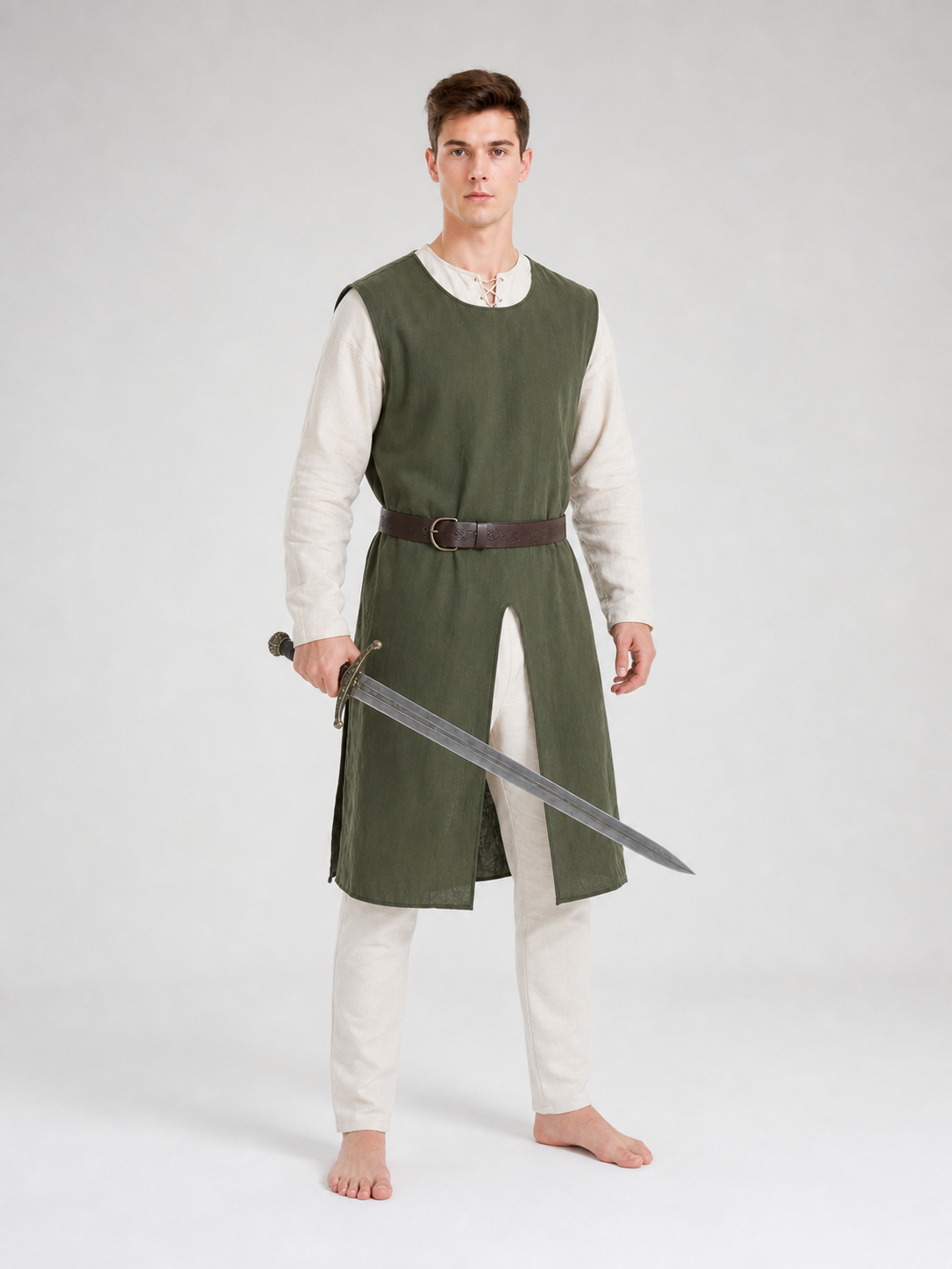 Full-body view of a man wearing a green sleeveless tunic over a white long-sleeve shirt with a brown belt