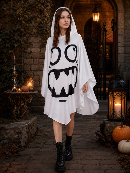 White hooded ghost poncho with a black face graphic and flowing sleeves, modeled outdoors in a Halloween-themed courtyard