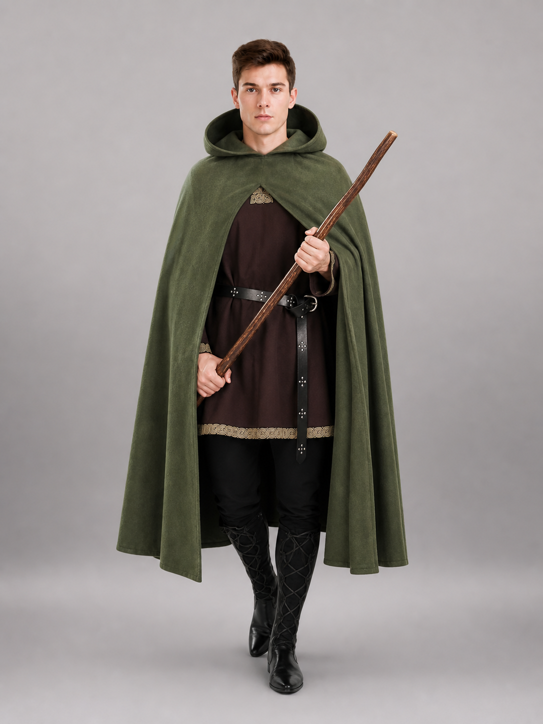 Dark olive hooded cape shown on a model holding a wooden staff, with an open front, draped panels, and a black belted tunic