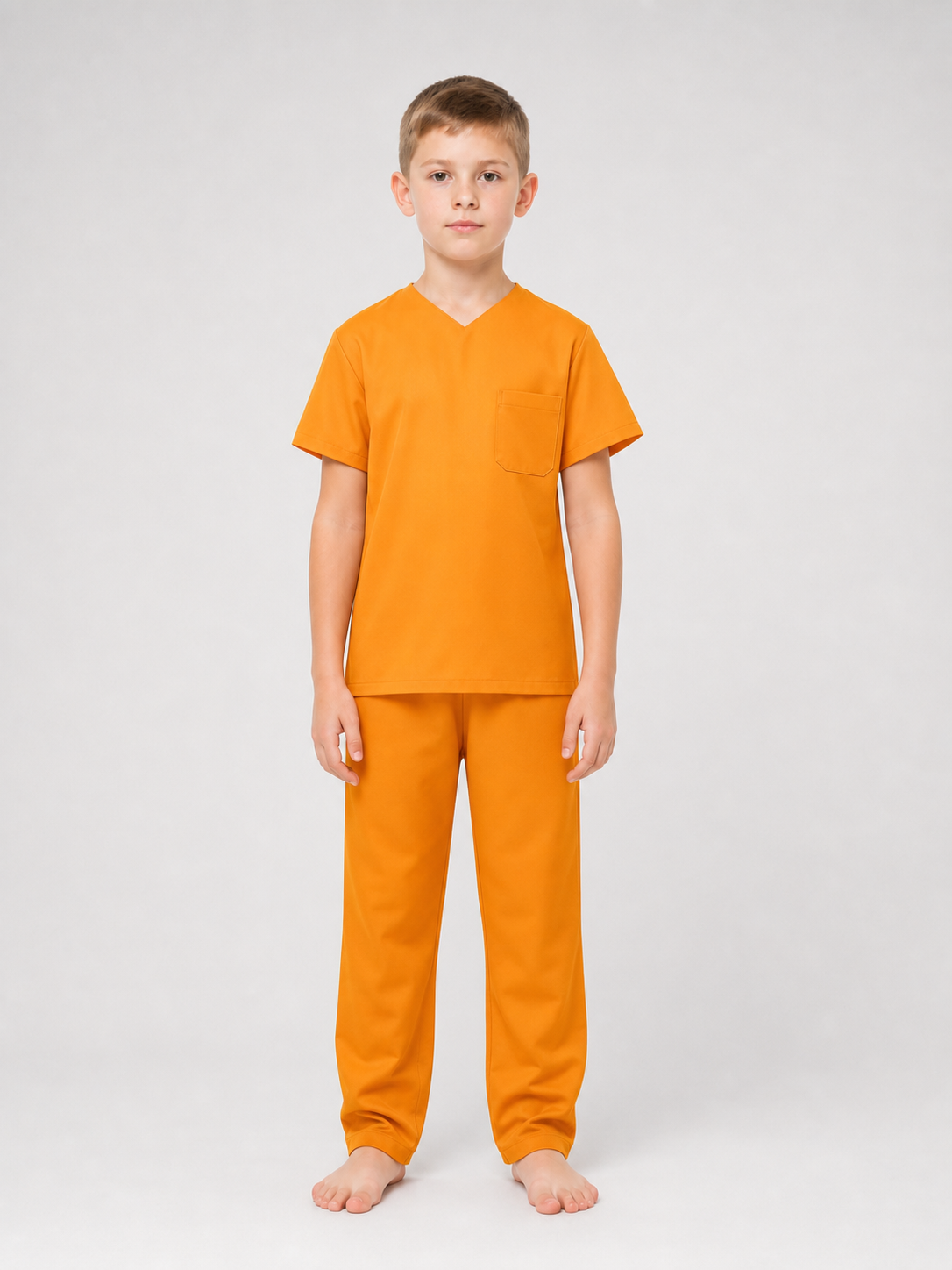Full-body studio view of a child wearing an orange V-neck shirt with chest pocket and matching pants, barefoot