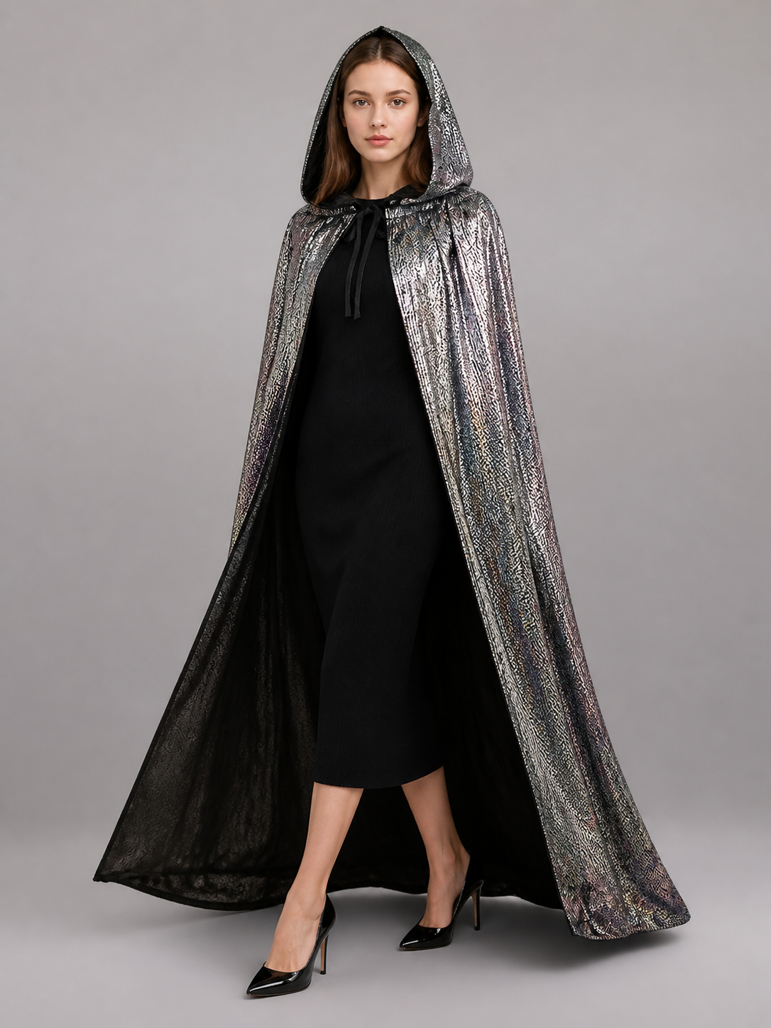 Silver metallic hooded cape shown full length on a model, worn with the hood up and black lining visible at the open front