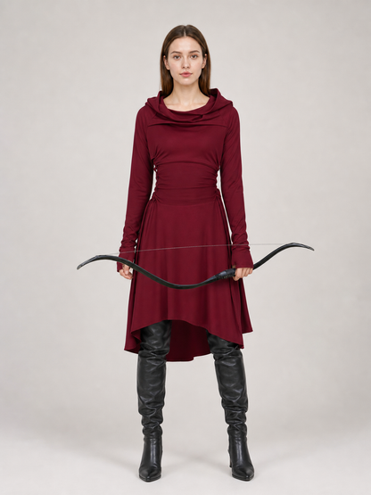 Burgundy hooded tunic in smooth fabric, shown full-body on a model with long sleeves, draped neckline, uneven hem, black boots, and a bow 2