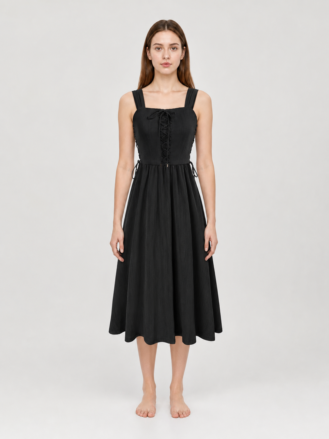 Black midi dress shown full-body on a model, with wide shoulder straps, lace-up bodice, side waist ties, and a gathered flowing skirt