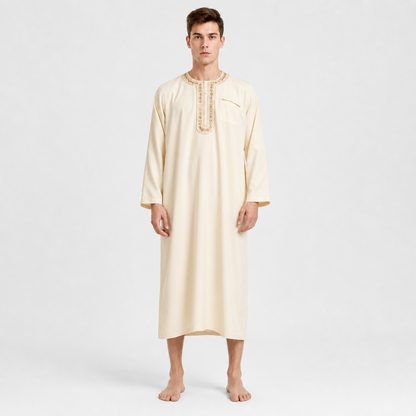 Cream ankle-length tunic robe with embroidered round neckline and long sleeves, shown full-body on a barefoot model