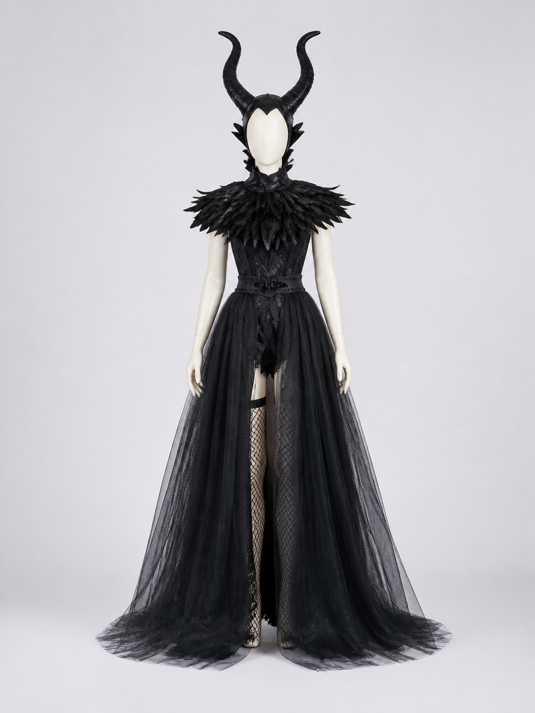 Front view of a black costume on a mannequin, featuring a horned headpiece, layered feather collar, fitted bodice, and sheer floor-length overskirt