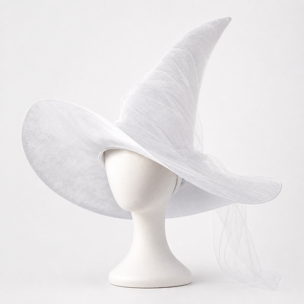 White sheer witch hat on a mannequin, with a wide floppy brim, tall curved crown, and trailing translucent veil