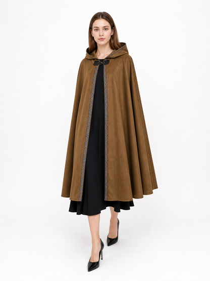 Brown suede-like hooded cape modeled against a white background, featuring a black center panel, patterned trim, and flared hem