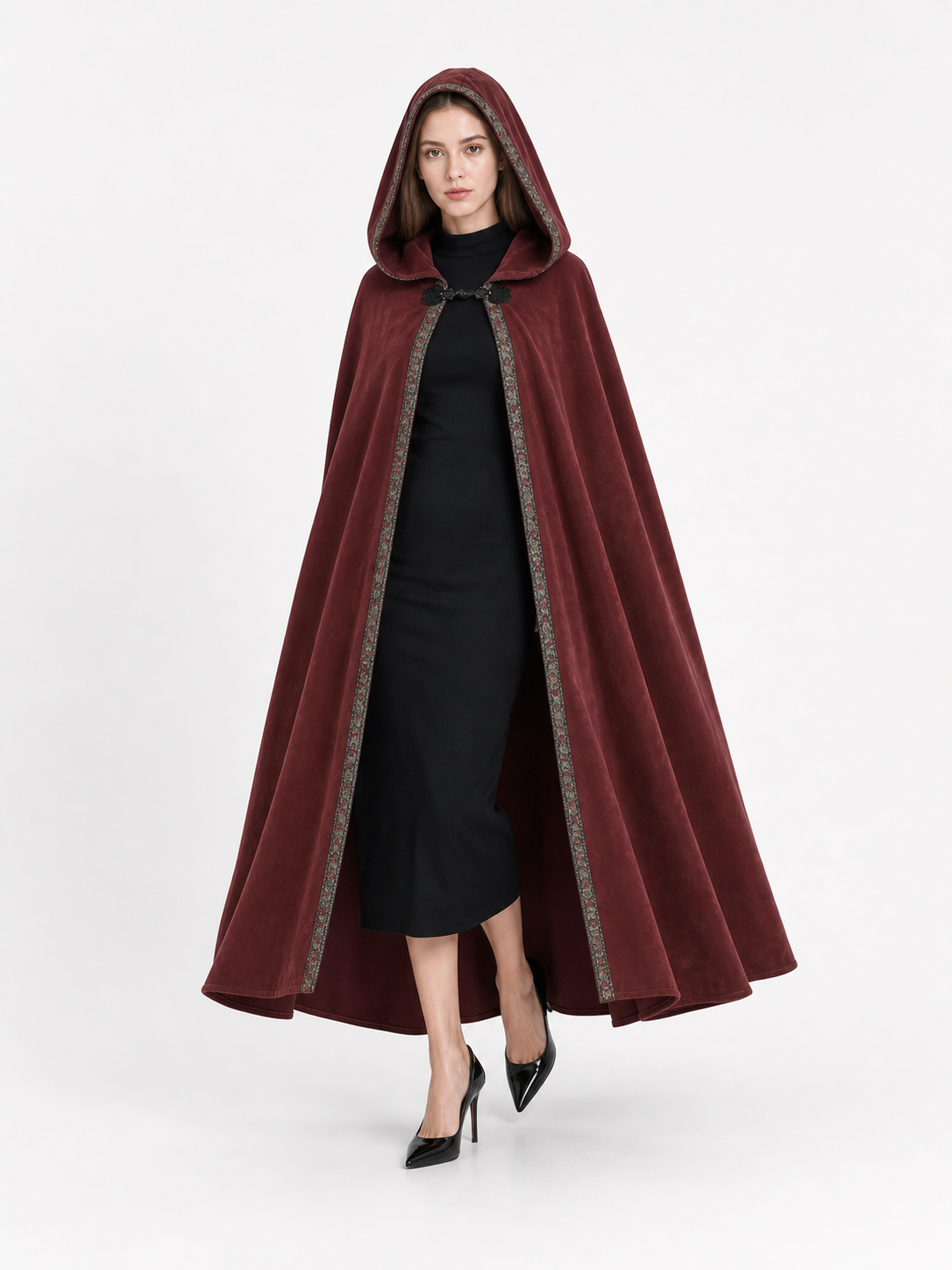 Burgundy velvet-look hooded cape on a full-body model, with patterned trim along the open front