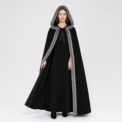 Black hooded cape with shaggy gray trim shown full-length on a model against a light studio background
