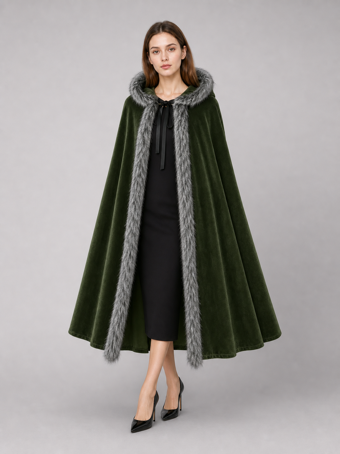 Olive green velvet-look hooded cape with gray faux-fur edging, shown front-facing on a model over a black dress
