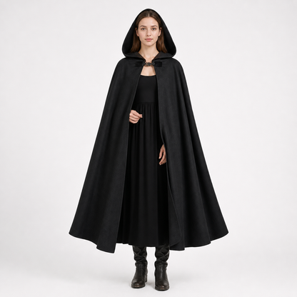 Black hooded cape shown full-length on a woman, with a flowing silhouette and decorative clasp at the neck