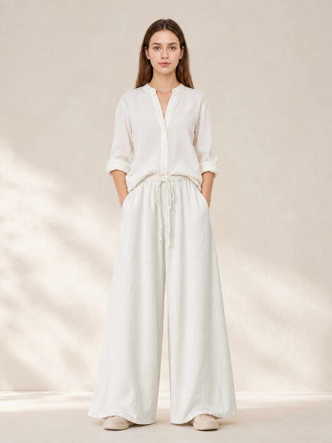 White wide-leg pants shown full-body on a model with a white blouse, side pockets, and a gathered drawstring waist
