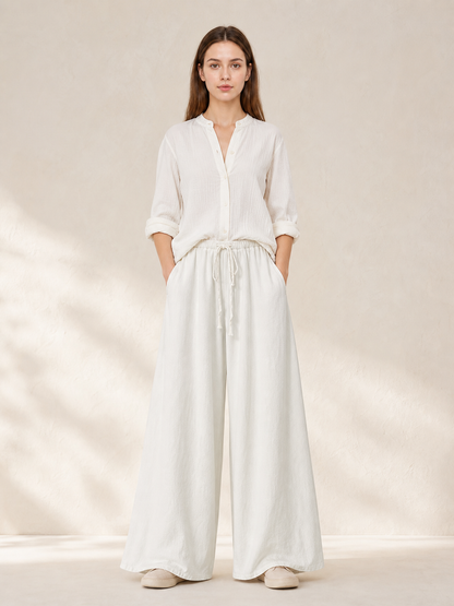 White wide-leg pants shown full-body on a model with a white blouse, side pockets, and a gathered drawstring waist