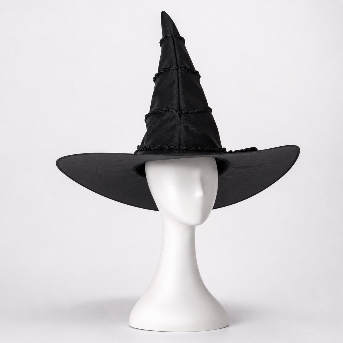 Black pointed witch hat with a wide floppy brim, displayed on a white mannequin stand against a light background