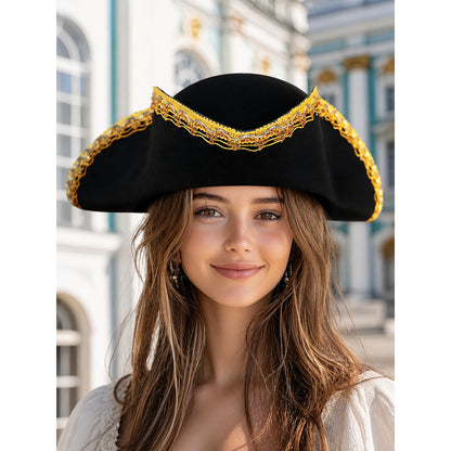 Black tricorn hat with ornate gold trim worn by a woman in front of a building