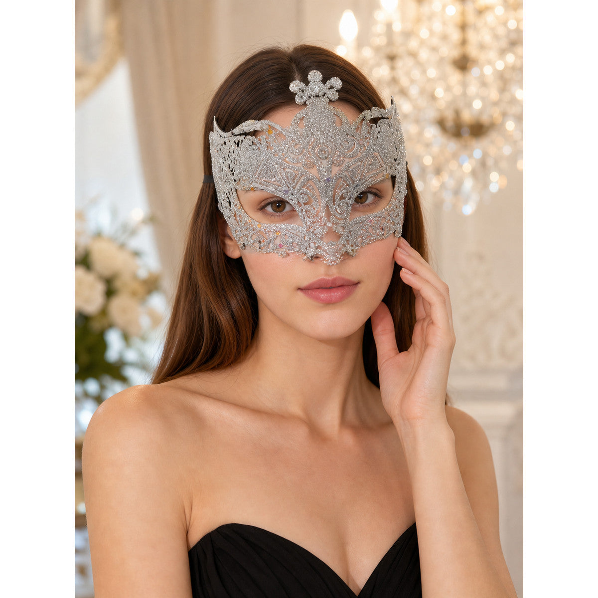 Silver glitter masquerade mask worn by a woman in a black strapless top, shown in a close-up styled scene with chandelier lights