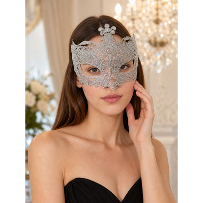 Silver glitter masquerade mask worn by a woman in a black strapless top, shown in a close-up styled scene with chandelier lights