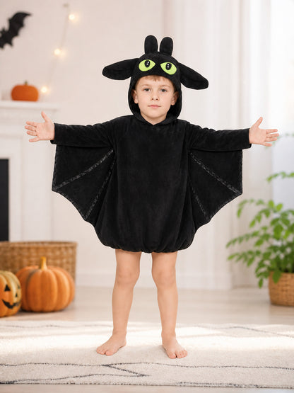 Black plush bat costume shown full-body on a child in a furnished room, with hood, ears, eyes, and wing panels
