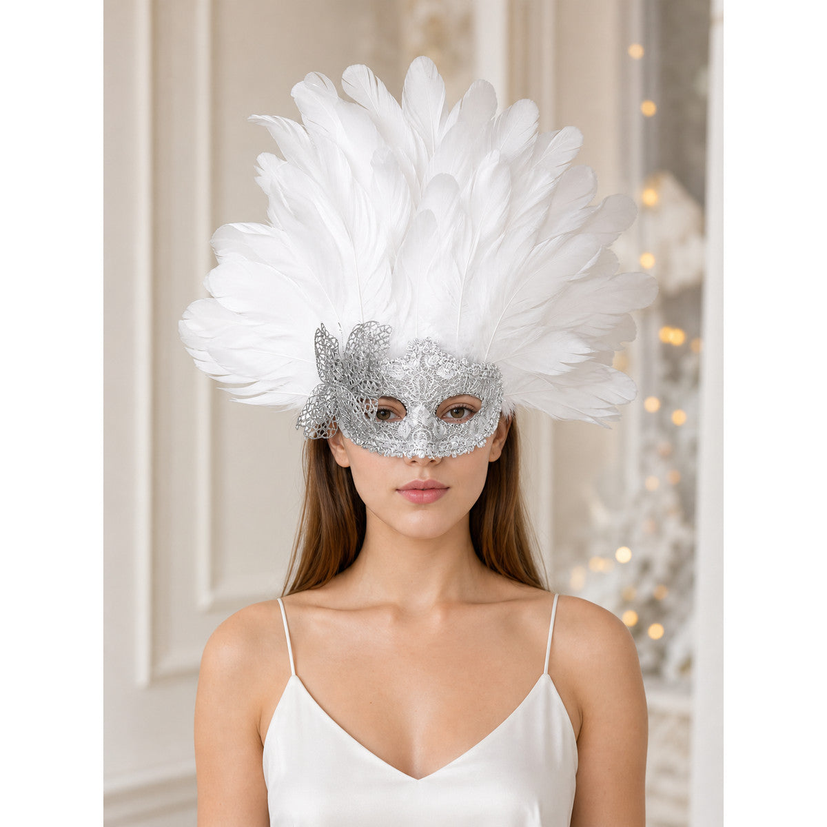 White feather and silver filigree masquerade mask worn front-facing by a model in a white camisole