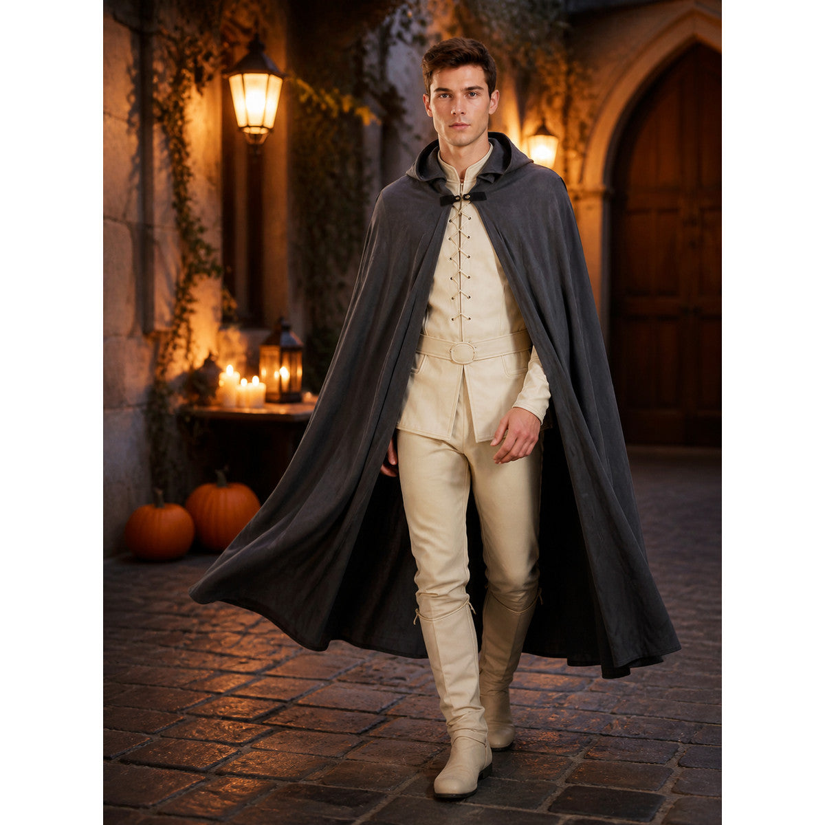 Dark gray hooded cape on a walking male model in a lantern-lit stone courtyard, with the cape flowing behind him