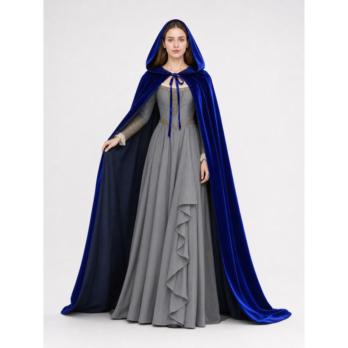 Blue velvet hooded cape worn open over a gray dress, showing the dark lining and front tie on a model