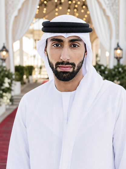White fabric headscarf with a double black agal, shown on a male model in a decorated indoor setting