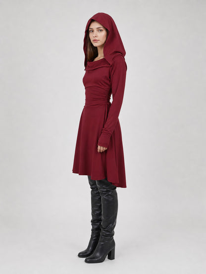 Burgundy hooded tunic in smooth fabric, shown in side view on a model with the hood raised, long sleeves, and an uneven hem