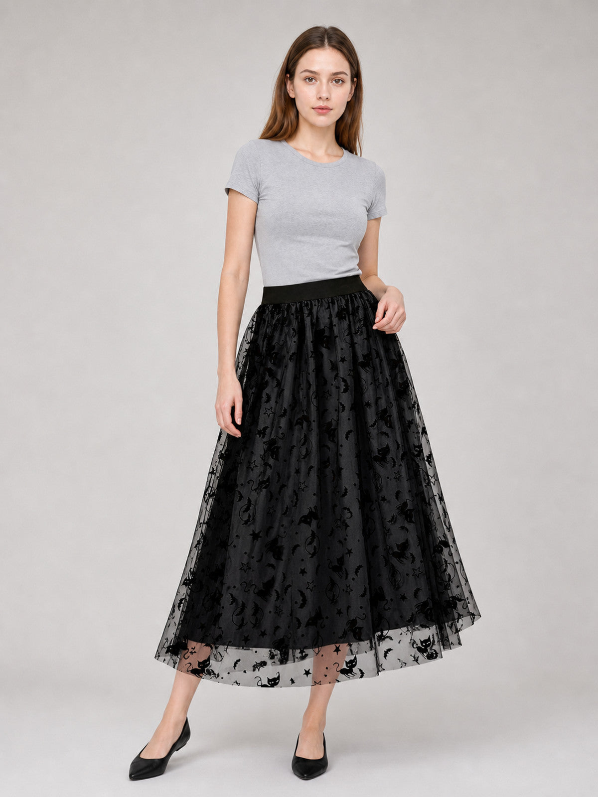 Black mesh midi skirt shown on a model with a gray top and black shoes, featuring a gathered waist and sheer patterned hem