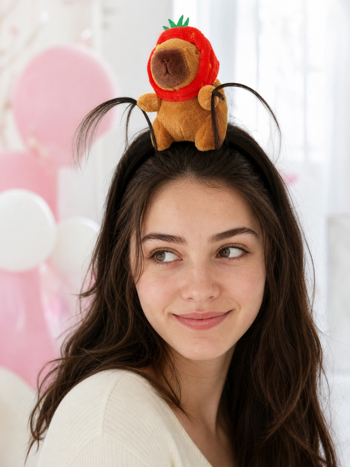 Plush brown animal headband with a red strawberry hood and green leaves, worn by a model in a softly styled indoor scene