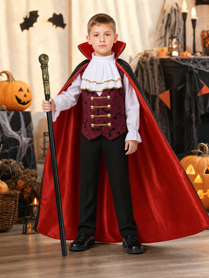 Boy wearing a burgundy vest, white ruffled shirt, and red-lined black cape in a Halloween scene with pumpkins and candles