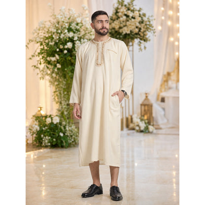 Cream embroidered long tunic robe with a chest pocket and side pocket, shown full-body on a model in a decorated indoor setting