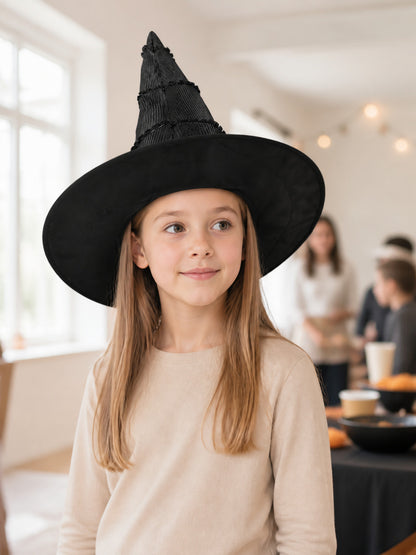 Black pleated pointed witch hat with a wide brim, shown on a child model in a softly lit indoor scene