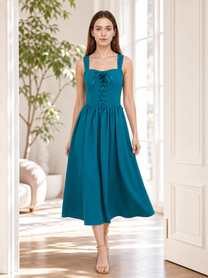 Teal strappy dress with lace-up bodice and flowing gathered skirt shown full-body on a model in a bright room