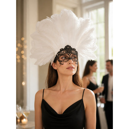 White feather headpiece with a black lace mask, shown on a model in a black dress at an indoor evening event