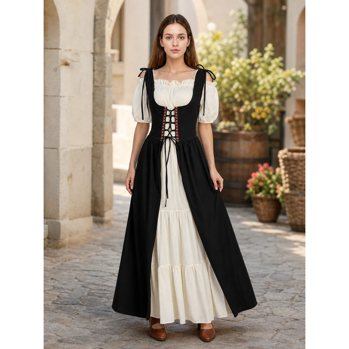 Front view of a black and cream lace-up dress with puff sleeves and a tiered cream skirt, modeled outdoors in a courtyard